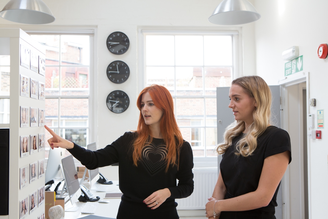 Esther and Tara discussing in the booking area of their workplace